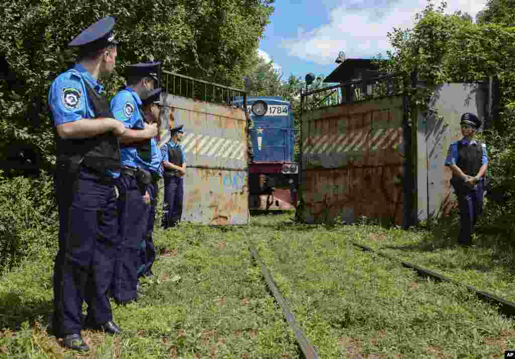 Police officers secure a refrigerated train loaded with bodies of the passengers of Malaysian Airlines flight MH17 as it arrives at a Kharkiv factory for a stop, July 22, 2014.