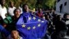 Un migrant portant un drapeau de l'Union européenne assis par terre avec d'autres après avoir pris d'assaut une clôture pour entrer dans l'enclave espagnole de Ceuta, Espagne, 17 février 2017.