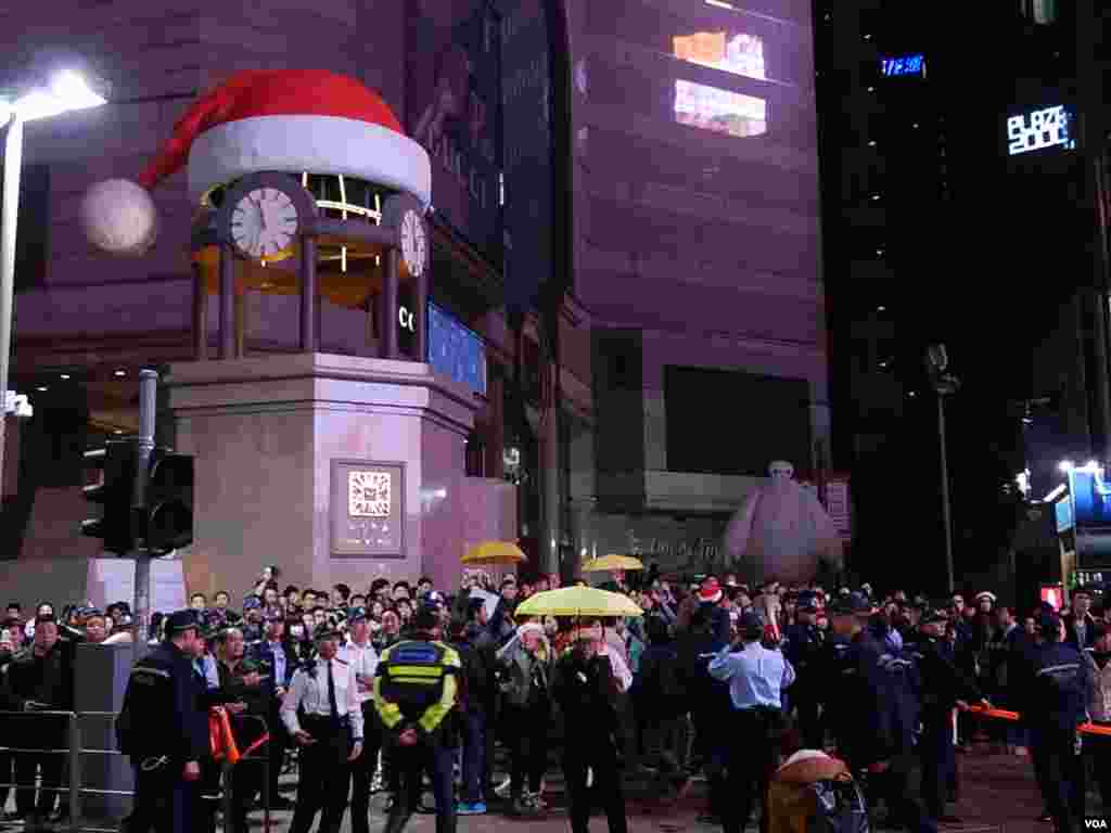 關上外牆電視屏幕及燈熄的銅鑼灣時代廣場,站滿平安夜報佳音及倒數的人群