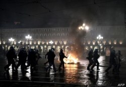 Policías cerca de un fuego encendido por manifestantes en una plaza de Turín, Italia.