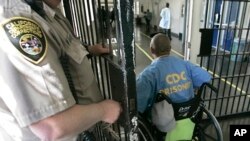 Archivo: En esta fotografía del 9 de abril de 2008, un privado de libertad atraviesa con su silla de ruedas uno de los puntos de control en el California Medical Facility, en Vacaville, Calif.