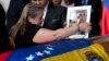 Liz Alban, hermana del ex concejal Fernando Alban, coloca un retrato de su pariente junto al de Jesucristo sobre su ataúd durante una ceremonia solemne en el Parlamento venezolano, el 9 de octubre de 2018, en Caracas.