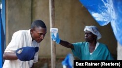 Un agent de santé mesure la température d'un homme entrant dans le centre de traitement Ebola à Beni, en République démocratique du Congo, le 1er avril 2019. 