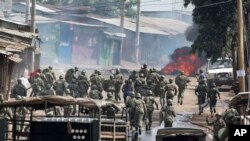 Des policiers kenyans pourchassent des manifestants qui ont érigé une barricade en flammes sur une rue, dans le bidonville de Kibera, à Nairobi, 23 mai 2016.