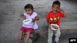 Dos niños comen algo el 8 de enero de 2021 en el caserío El Buen Samaritano, municipio de La Lima, Departamento de Cortés, Honduras, zona afectada por los huracanes Eta e Iota en 2020.