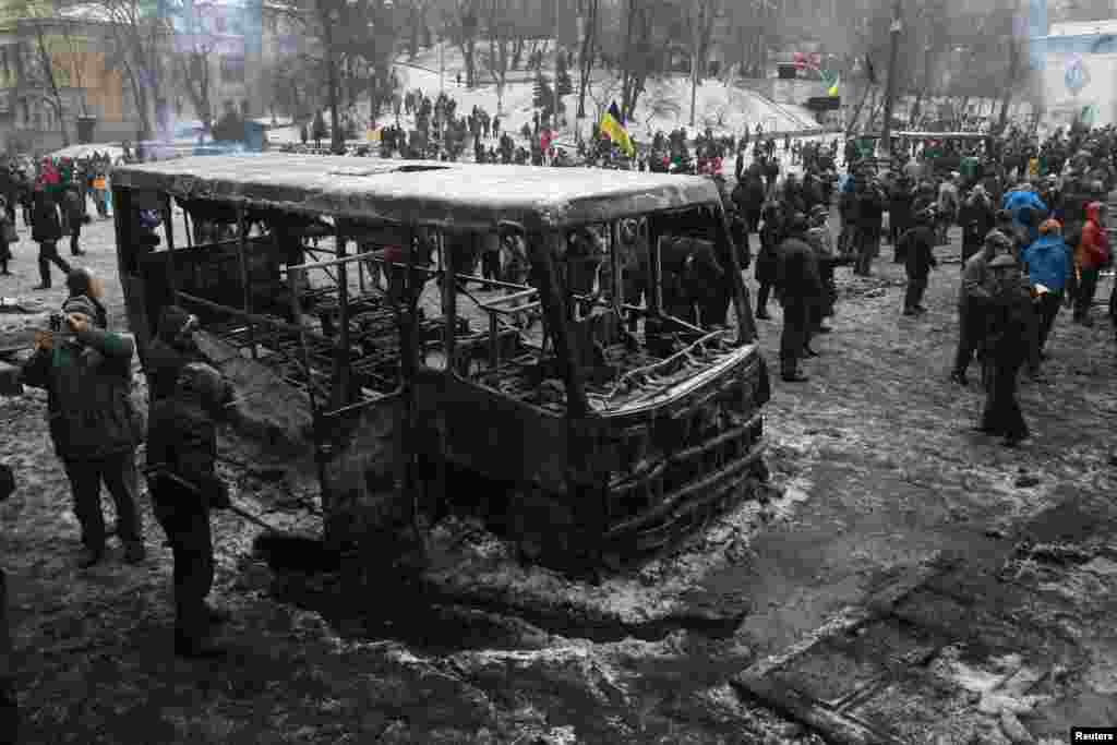 Protesters gather near a bus that was burned during demonstrations organized by pro-European integration supporters in Kyiv, Jan. 21, 2014.