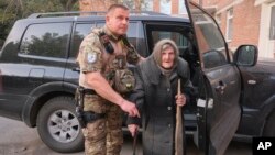 En esta fotografía proporcionada por la Policía Nacional Ucraniana de la región de Donetsk, Lidia Lomikovska, de 98 años, recibe ayuda de un oficial de policía ucraniano después de escapar del territorio ocupado por Rusia en la región de Donetsk, Ucrania, el 26 de abril de 2024.
