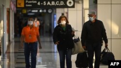 Los pasajeros en el Aeropuerto Internacional San Oscar Romero en San Luis Talpa, El Salvador, usan máscaras faciales como precaución contra la propagación del nuevo coronavirus, COVID-19, el 12 de marzo de 2020. [AFP]