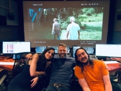 María Carolina Santana con dos compañeros de su equipo frente a una proyección de la película Sound Of Metal. Foto cortesía de María Carolina Santana.