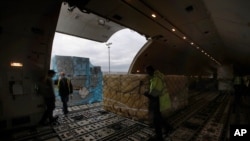 FILE - Air France cargo workers load equipment and pharmaceutical containers in a cargo plane at Roissy airport, outside Paris, Nov. 25, 2020, as the company is preparing for the transport of COVID-19 vaccines.