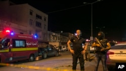 FILE - Tunisian police officers stand guard after police shot at a man wanted for terrorism in Al Intilaka, near Tunis, Tunisia, July 2, 2019. 