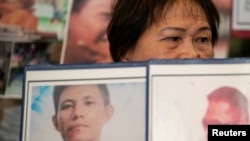 Llore Pasco sostiene fotografías de sus dos hijos, víctimas de la guerra contra las drogas y de ejecuciones extrajudiciales. Visto tras el arresto del expresidente filipino Rodrigo Duterte, en Ciudad Quezón, Metro Manila, Filipinas, el 12 de marzo de 2025.