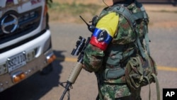 ARCHIVO - Guerrilleros de las FARC-EMC imponen un control de carretera en Corinto, Colombia, el viernes 12 de abril de 2024, el día después de que un coche bomba explotara en la cercana ciudad de Miranda.