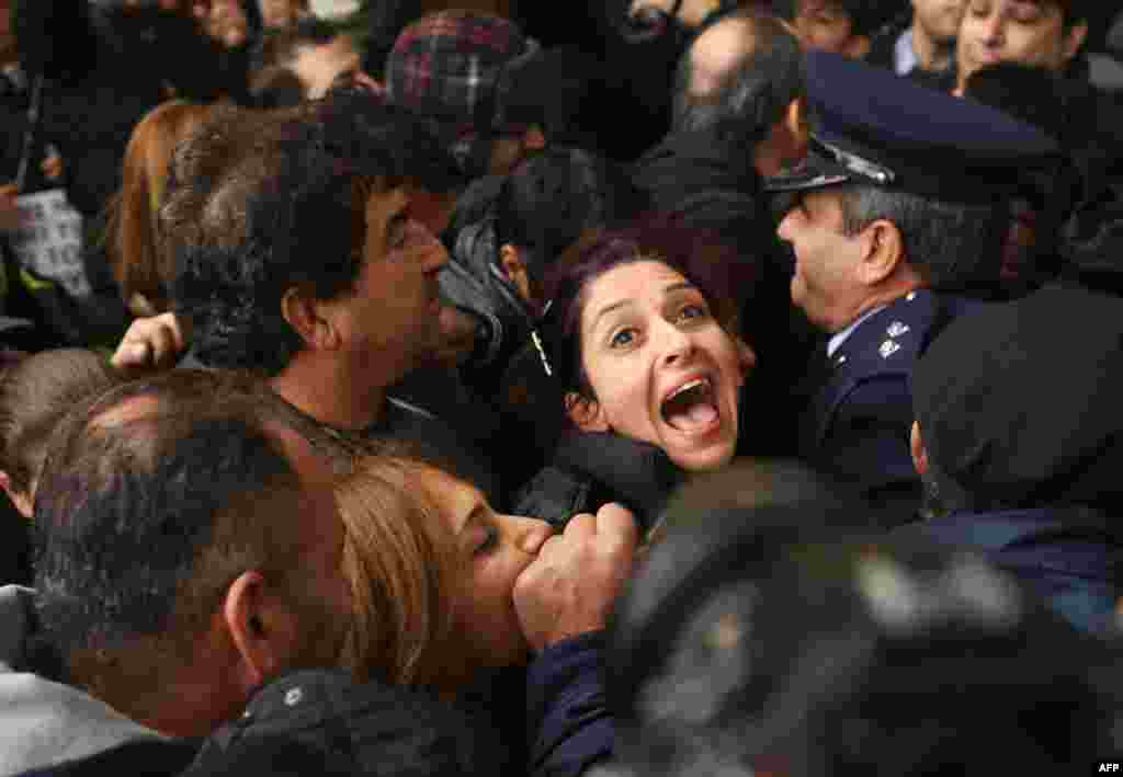 A Cyprus Airways employee shouts as she is pushed against a police line at the Ministry of Finance in Nicosia during a protest against the closing down of the airline.