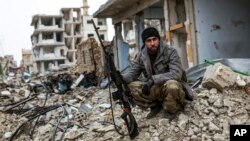 A Syrian Kurdish sniper sits among the rubble in the Syrian city of Kobani, Jan. 30, 2015.