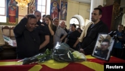 Keluarga polisi yang ditembak Sasho Samoilovski berduka di dekat peti matinya yang ditutupi bendera Macedonia di sebuah gereja di Tetovo, Macedonia, 10 Mei 2015.