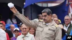 El presidente Nicolás Maduro lanza un pañuelo a sus partidarios durante un acto por el 165 aniversario de la Batalla de Santa Inés, en Caracas, Venezuela, el martes 10 de diciembre de 2024. (Foto AP/Ariana Cubillos)