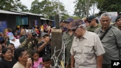 El presidente electo panameño, José Raúl Mulino, habla con un migrante venezolano (izq.) y otros migrantes en un campamento después de cruzar caminando el Tapón del Darién desde Colombia, en Lajas Blancas, Panamá, el viernes 28 de junio de 2024. 