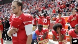 FILE - San Francisco 49ers quarterback Blaine Gabbert, left, stands as Eli Harold, from bottom left, Colin Kaepernick and Eric Reid kneel during the national anthem before an NFL football game in Santa Clara, California, Oct. 2, 2016.