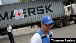 Para relawan berdiri dekat truk kontainer makanan berlogo Federasi Masyarakat Palang Merah dan Bulan Sabit Merah Internasional yang tiba membawa bantuan kemanusiaan di Caracas, Venezuela, 31 Juli 2019.
