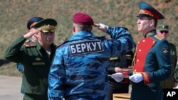 A photo provided by the Russian Defense Ministry shows Russian Defense Minister Sergei Shoigu (L) awarding a former Ukrainian special forces "Berkut" officer (back to camera) at a military base in Sevastopol, Crimea, March 24, 2014.