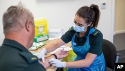 La paramédico Jess Baddams toma una muestra de sangre de Tony Oliver durante una prueba para el coronavirus en Birmingham, Inglaterra.