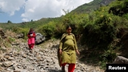 ARCHIVO - Una mujer embarazada baja una montaña después de votar en un colegio electoral remoto en Almi, la India, el 1 de junio de 2024, durante una ola de calor a nivel nacional.