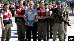 FILE - paramilitary police and members of the special forces escort former Air Force commander Akin Ozturk and other suspects of last year's failed coup, outside the courthouse at the start of a trial, in Ankara, Turkey. 