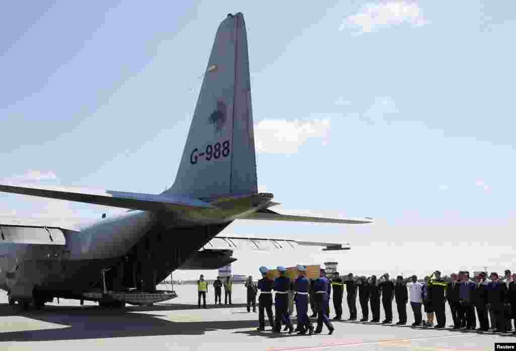Honor guards carry a coffin of one of the victims of Malaysia Airlines MH17 before loading it on a transport plane heading to the Netherlands, at Kharkiv Airport, July 23, 2014. 
