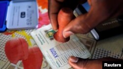 Un agent électoral appose le sceau sur le bulletin d’un électeur qui vient de voter lors des législatives à Abidjan, Côte d’Ivoire, 18 décembre 2016.