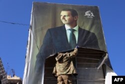 Seorang militan antipemerintah merobek potret Presiden Suriah Bashar al-Assad di Aleppo, 30 November 2024, setelah jihadis dan sekutunya memasuki kota tersebut. (Foto: AFP)