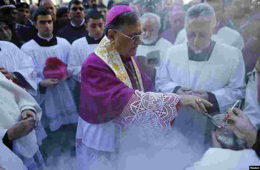 The Latin Patriarch of Jerusalem Fouad Twal (C) prepares to bless the crowd outside the Church of the Nativity in the West Bank city of Bethlehem, December 24, 2012.