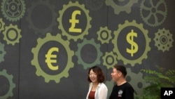 Mural di sebuah bank bersimbol mata uang berbagai negara, termasuk dolar (Amerika) dan yuan (China), di Beijing, China, 7 Juli 2018. (Foto: dok). 