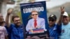 Dos militantes del partido opositor Un Nuevo Tiempo muestran un afiche con la imagen del candidato presidencial Edmundo González Urrutia durante una concentración con el postulado y la dirigente María Corina Machado en Aragua, el 18 de mayo de 2024.