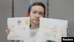 La periodista estadounidense-rusa de Radio Free Europe/Radio Liberty (RFE/RL) Alsu Kurmasheva, sostiene dibujos de sus seguidores mientras asiste a una audiencia judicial en Kazán, Rusia, el 31 de mayo de 2024.