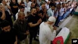 Dolientes palestinos rezan junto al cuerpo de Mohammad Hoshiya, de 12 años, durante su funeral en la aldea cisjordana de Qatana, al suroeste de Ramala, el 22 de junio de 2024.
