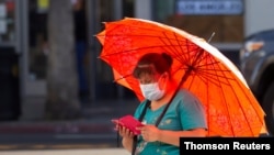 A person wearing a protective face mask uses her mobile phone during the outbreak of the coronavirus disease (COVID-19), in Los Angeles