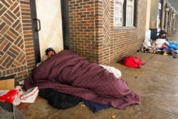 People living on the streets use blankets to keep warm, Feb. 18, 2021, in downtown San Antonio, Texas. Snow, ice and subfreezing weather continue to wreak havoc on the state's power grid and utilities.