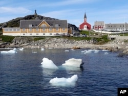 In this image taken on June 13, 2019 small pieces of ice float in the water off the shore in Nuuk, Greenland.