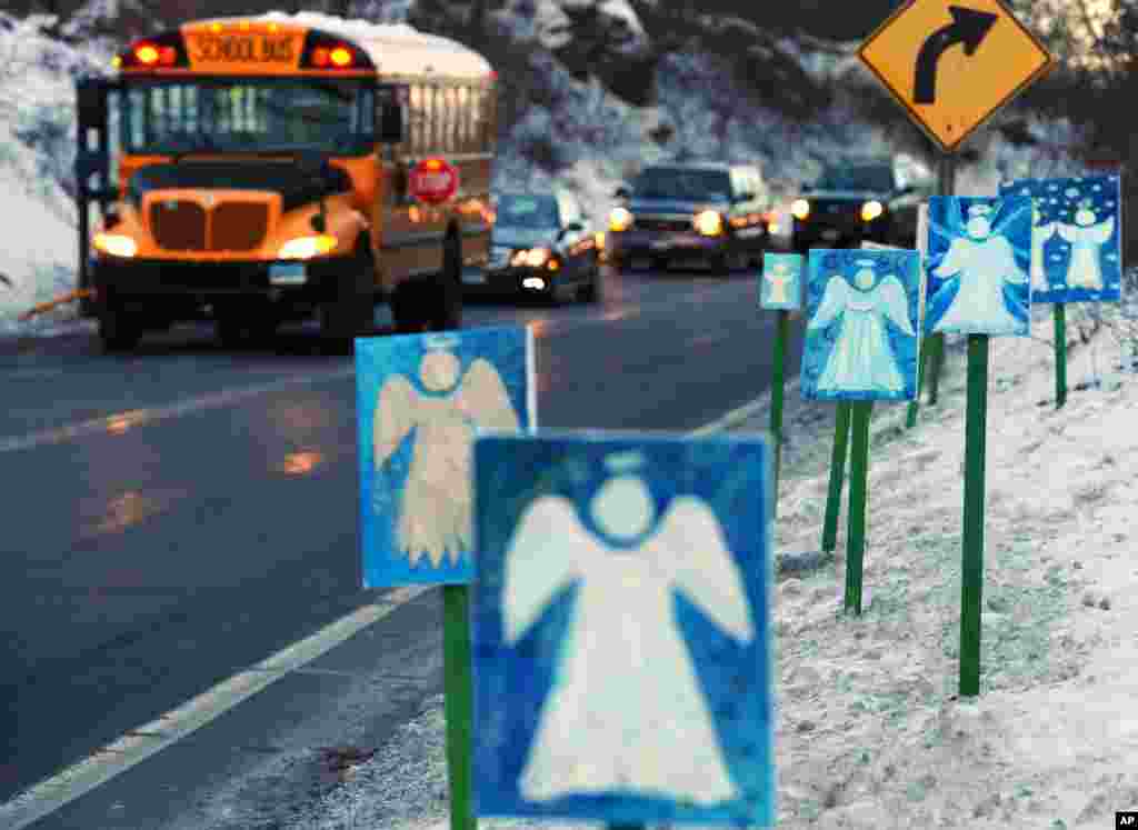 Bus sekolah yang membawa siswa-siswa SD Sandy Hook dari Newtown ke Monroe berhenti di depan 26 papan bergambar malaikat di pinggir jalan pada hari pertama sekolah sejak penembakan 14 Desember 2012.