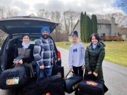 In this April 1, 2020 photo provided by Paramjyoti Kaur Singh, Singh family members Baani, Shalinder, Arjun and Jasveen Kaur pose for a photo before delivering pizzas to health care workers.