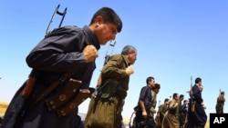 FILE - Kurdish Peshmerga security forces stand guard on the outskirts of the northern city of Mosul, Iraq.
