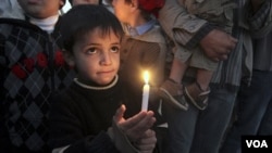 Seorang anak laki-laki Palestina memegang lilin dalam peringatan 2 tahun serangan tiga minggu Israel ke Gaza, 27 Desember 2010.