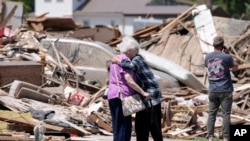 ARCHIVO - Joan Mitchell, izquierda, recibe un abrazo de su vecina Edith Schaecher frente a sus casas dañadas por el tornado, el jueves 23 de mayo de 2024, en Greenfield, Iowa.
