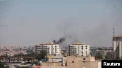 Asap membumbung dekat gedung-gedung menyusul pertempuran hebat antara dua kelompok milisia di Tripoli, Libya (20/7). (Reuters/Hani Amara)