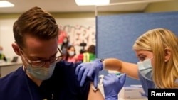 Mahasiswa kedokteran tahun keempat Anna Roesler sedangan menggunakan vaksin Pfizer-BioNTech COVID-19 di Indiana University Health, Methodist Hospital di Indianapolis, Indiana, AS, 16 Desember 2020. (Foto: REUTERS/Bryan Woolston)