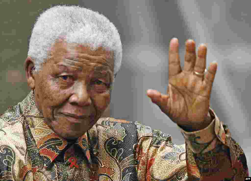 Nelson Mandela waves to the media as he arrives outside 10 Downing Street, London, August 28, 2007.