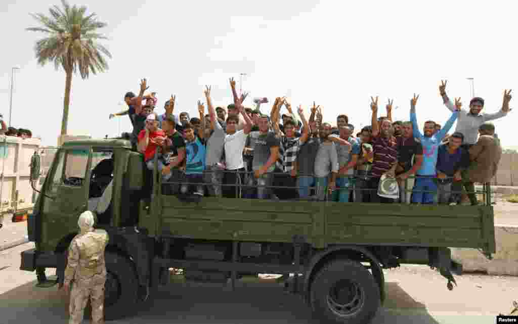 Volunteers who have joined the Iraqi Army to fight against the predominantly Sunni militants gesture from an army truck, Baghdad, June 13, 2014. 