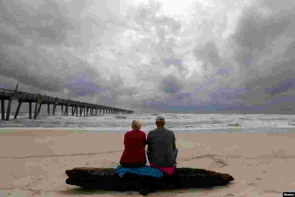 A local couple, who asked not to be named, watch waves come ashore in advance of Hurricane Michael in Pensacola, Florida, Oct. 9, 2018.