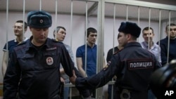 Defendants stand in courtroom cage, Moscow, Feb. 21, 2014.